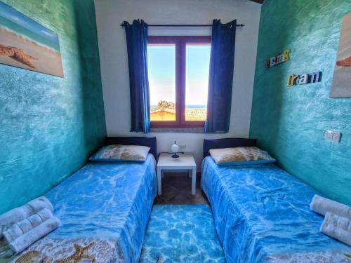 two beds in a room with a window at La Perla e le Conchiglie Tanca Piras vista mare in Nebida