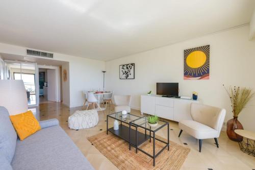 un salon avec un canapé et une télévision dans l'établissement 1-Br apartment calm sea view pool and parking garage, à Cannes