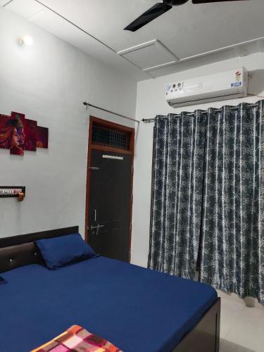 - une chambre avec un lit bleu et une fenêtre dans l'établissement SiyaRam Homestay, à Faizābād