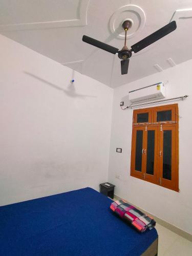 Cette chambre comprend un lit et un ventilateur de plafond. dans l'établissement SiyaRam Homestay, à Faizābād