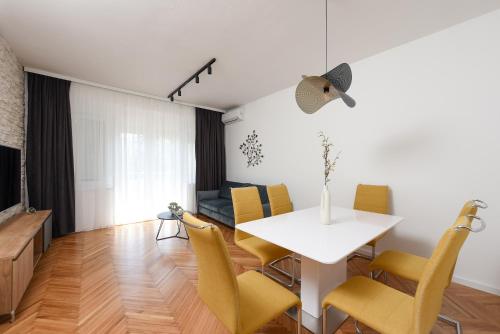 een eetkamer en een woonkamer met een witte tafel en gele stoelen bij Apartment Monika in Zadar