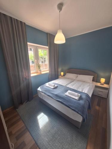 a blue bedroom with a bed and a window at Apartman Lilium in Knin