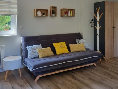 a black couch in a living room with yellow pillows at CDG Aparts in Le Mesnil-Amelot