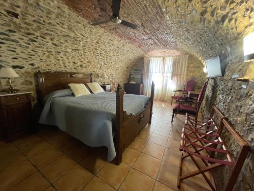 a bedroom with a bed in a stone wall at Can Garriga in Garriguella