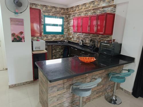 a kitchen with red cabinets and a counter with stools at Paradise Gates Golden Beach two in Ras Sedr