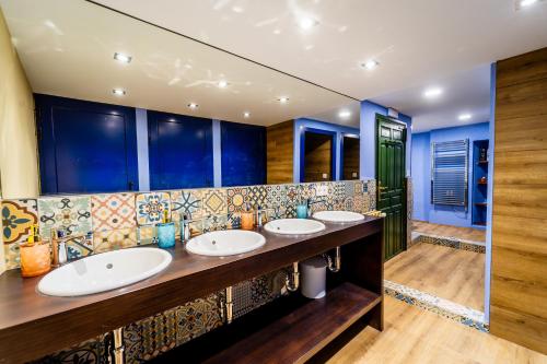 łazienka z 3 umywalkami i niebieskimi ścianami w obiekcie Albergue INpulso Atapuerca w mieście Atapuerca