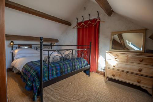 a bedroom with a bed and a dresser and a mirror at Y Granor in Pwllheli