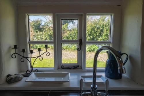 encimera de cocina con fregadero y ventana en The Longhouse, en Pwllheli