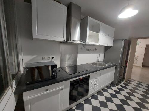 une cuisine avec des placards blancs et un sol en damier noir et blanc dans l'établissement Ananas Souriant, nearby Paris,Disneyland,Outlet, à Fontenay-sous-Bois