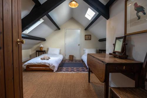 1 dormitorio en el ático con 2 camas y espejo en The Longhouse, en Pwllheli