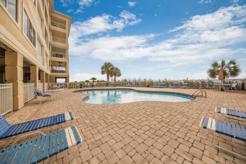 a swimming pool with blue chairs and a building at Marlin Key 4C by Vacation Homes Collection in Orange Beach
