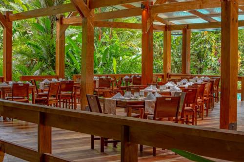 a restaurant with wooden tables and chairs on a wooden deck at Chachagua Rainforest Hotel & Hot Springs in Fortuna