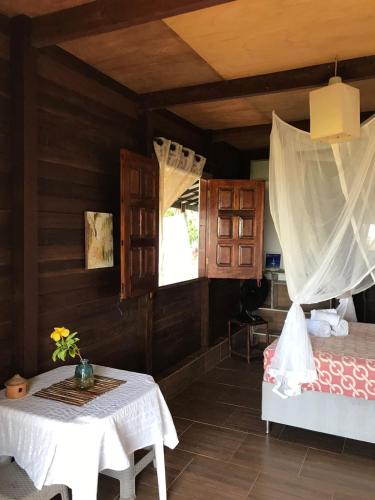 Cette chambre comprend un lit, une table et une fenêtre. dans l'établissement Belissima Suite frente ao mar, Praia Linda Gamboa, à Cairu
