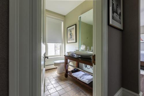 een badkamer met een wastafel, een toilet en een spiegel bij The Centennial Hotel in Concord