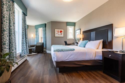 una habitación de hotel con una cama grande y una silla en The Centennial Hotel, en Concord