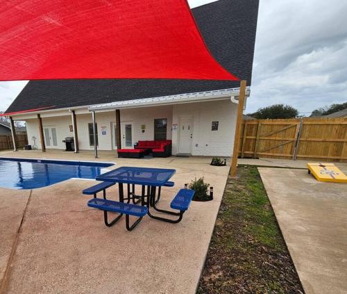 una mesa de picnic frente a una casa con piscina en Louisiana 5BR Luxury Pool Retreat, en Lake Charles