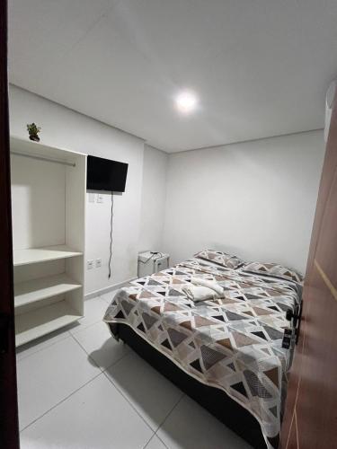 a bedroom with a bed and a flat screen tv at Suite Em Maragogi (pousada) in Maragogi