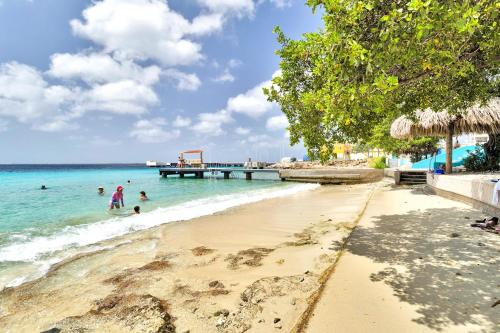 a beach with people in the water and a pier at Chachacha Ocean View Apartment on the Sea in Kralendijk
