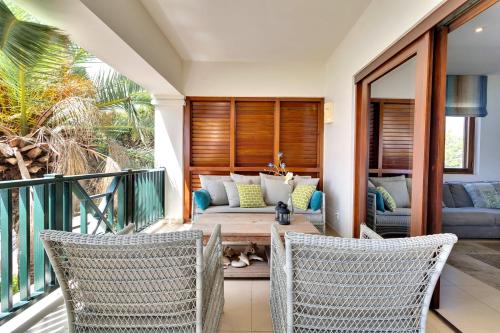 a patio with a couch and chairs on a balcony at Chachacha Ocean View Apartment on the Sea in Kralendijk