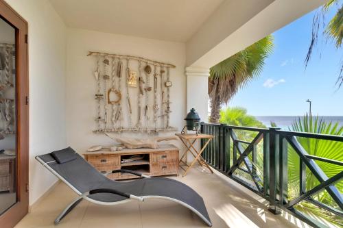 a chair on a balcony with a view of the ocean at Chachacha Ocean View Apartment on the Sea in Kralendijk