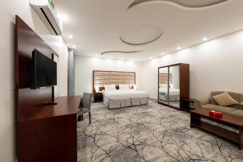 فندق مشارف أبها سويتس في أبها: غرفة نوم بسرير وتلفزيون وأريكة