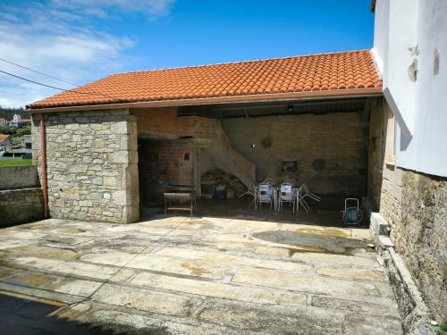 un edificio de piedra con un patio con sillas. en Casa da Riba da Lama Niñons ,Costa da Morte, en Ponteceso
