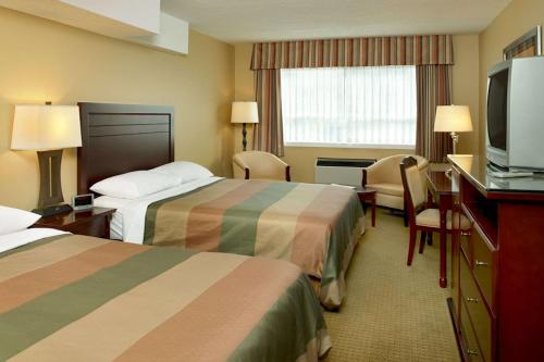 a hotel room with two beds and a flat screen tv at Coast Fraser Inn in Williams Lake