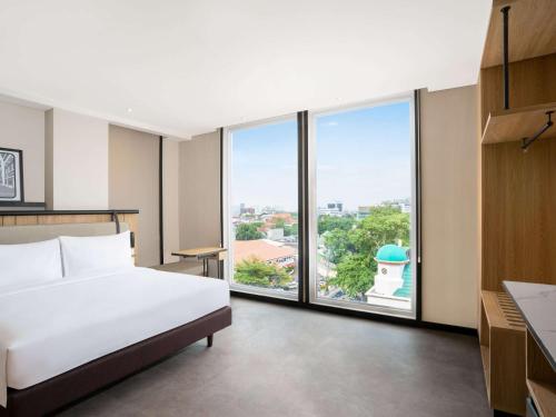 ジャカルタにあるibis Jakarta Raden Salehのベッドと大きな窓が備わるホテルルームです。