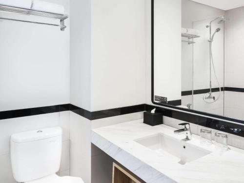 a white bathroom with a toilet and a sink at ibis Jakarta Raden Saleh in Jakarta