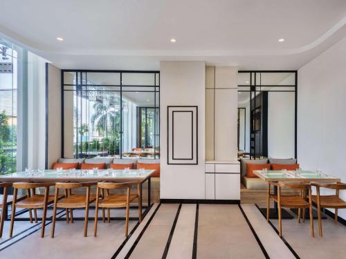 a dining room with tables and chairs and windows at ibis Jakarta Raden Saleh in Jakarta