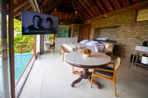 - un salon avec une télévision, un lit et une table dans l'établissement Lodge Prainha, Praia de Gravatá, à Gravatá