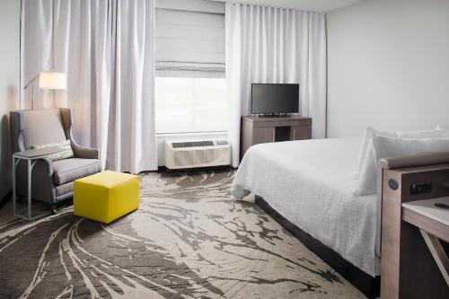 a bedroom with a bed and a chair and a television at Hilton Garden Inn Dallas/Arlington South in Arlington