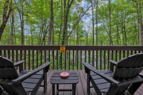 2 Stühle und ein Tisch auf einer Terrasse mit Bäumen in der Unterkunft Lakefront Cabin Bordering Nat Park with Hot Tub! cabin in Turtletown