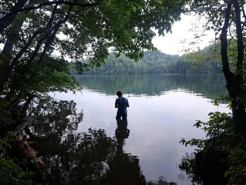 a man standing in the middle of a lake at Lakefront Cabin Bordering Nat Park with Hot Tub! cabin in Turtletown