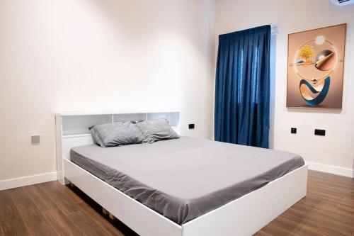 Modern Townhouse near Beach في آكرا: سرير أبيض في غرفة نوم ذات ستارة زرقاء