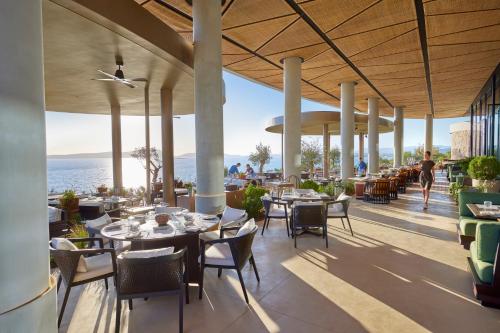 a restaurant with tables and chairs and a view of the ocean at Mandarin Oriental, Costa Navarino in Pylos
