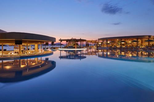 a resort with a pool with tables and buildings at Mandarin Oriental, Costa Navarino in Pylos