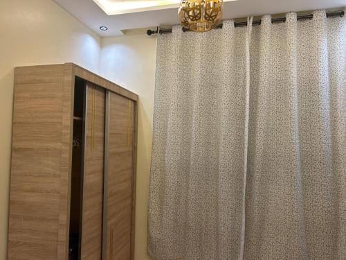 a room with a dresser and a curtain and a chandelier at Appart Flora in Tangier