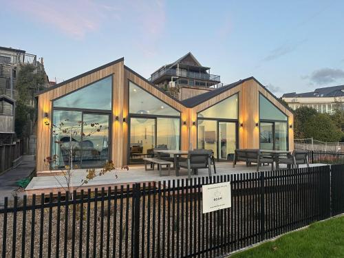 a house with glass windows and a table and benches at Absolute Lakefront House in Taupo