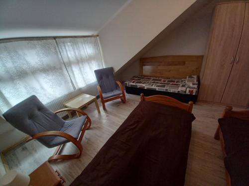 uma sala de estar com duas cadeiras e uma cama em Pokoje gościnne u Anka Reszel em Reszel