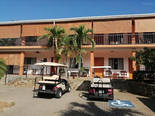 dos carros de golf estacionados frente a un edificio en Bolimar at Playa Hermosa, Guanacaste, en Playa Hermosa