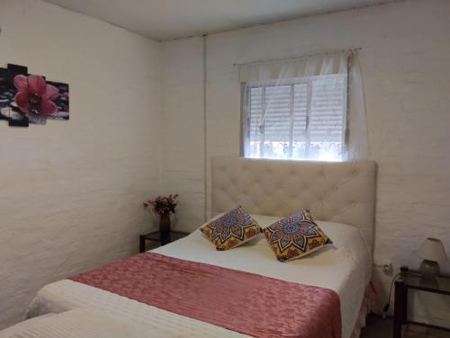 a bedroom with a bed with two pillows and a window at Lugar tranquilo in Colonia del Sacramento
