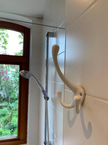 uma cabeça de chuveiro numa casa de banho ao lado de uma janela em Gästehaus EinsA em Celle