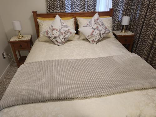a bed with pillows and two nightstands with two lamps at BARNES STREET BNB in Timaru