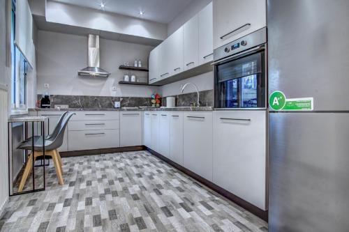 a kitchen with white cabinets and a table and a refrigerator at AnGio City House in Análipsis