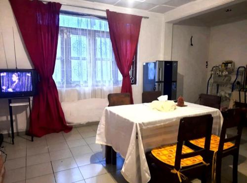 康提的住宿－Kandyan Paradise，一间设有白色桌子和红色窗帘的用餐室