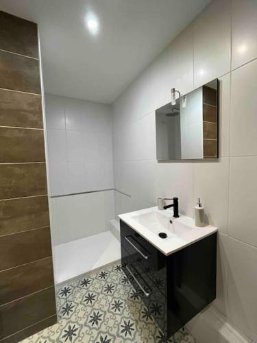 une salle de bain blanche avec un lavabo et un miroir dans l'établissement Le grand arc, proche centre ville, à Albertville