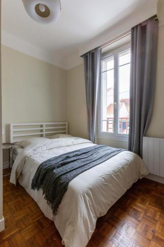 une chambre avec un lit et une grande fenêtre dans l'établissement Appartement 3 pièces - Proche RER et centre ville, à Corbeil-Essonnes