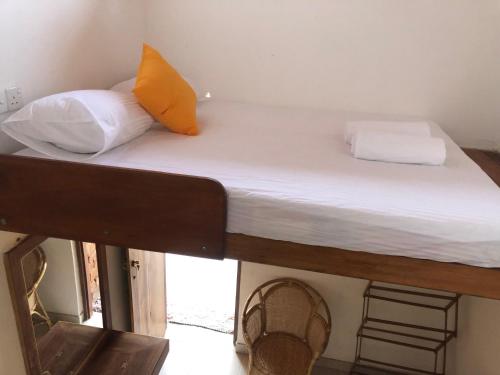 a bed with white sheets and an orange pillow on it at RedBrick House Rumassala in Galle