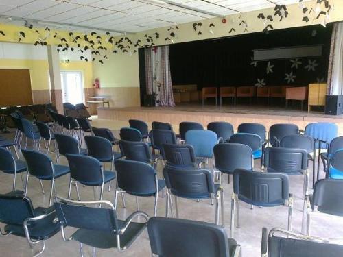 a room with blue chairs and a stage with at Remniku Holiday Centre in Remniku